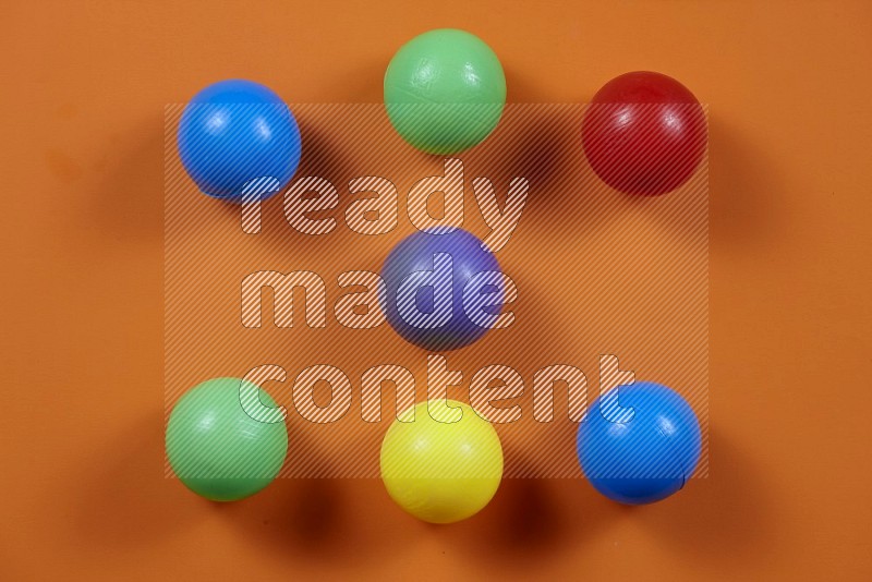 Multicolored plastic balls on yellow background in top view (kids toys)
