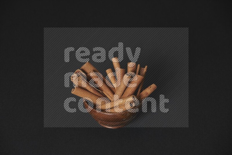 Cinnamon Sticks in a wooden bowl on black background