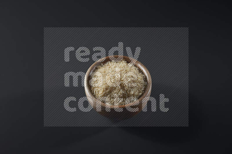 Basmati golden rice in a wooden bowl on grey background