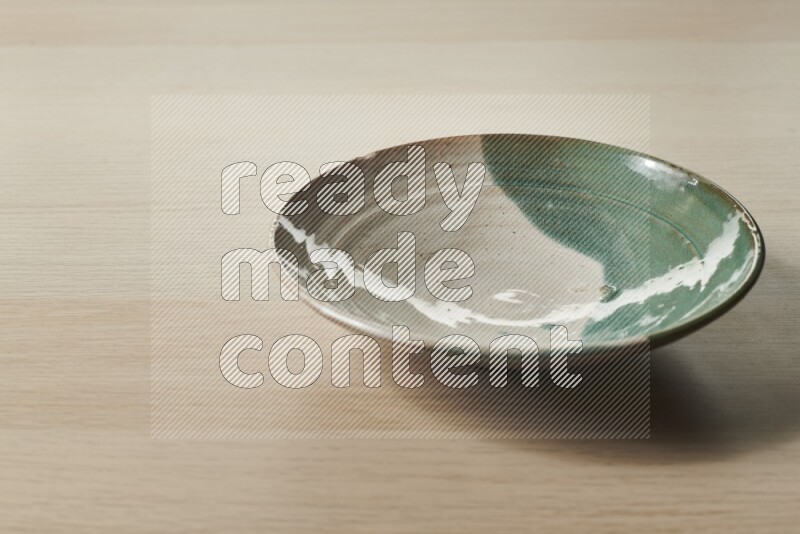 A multicolored pottery plate on light wooden background