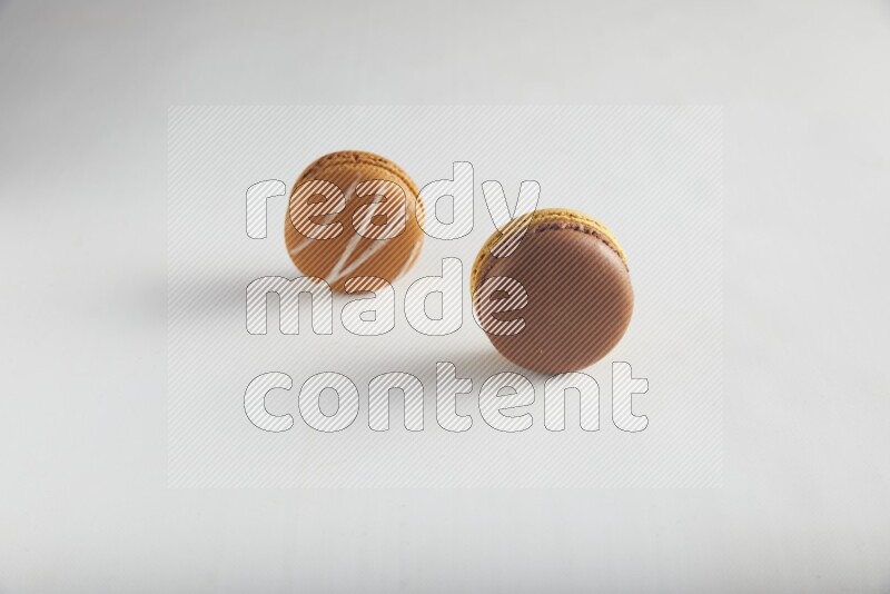 45º Shot of of two assorted Brown Irish Cream, and Yellow, and Brown Chai Latte macarons on white background