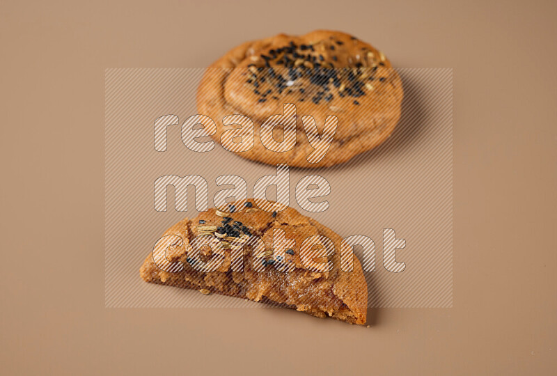 a Hasawi cookie field of date and herbs with another one cut in half on a brown background