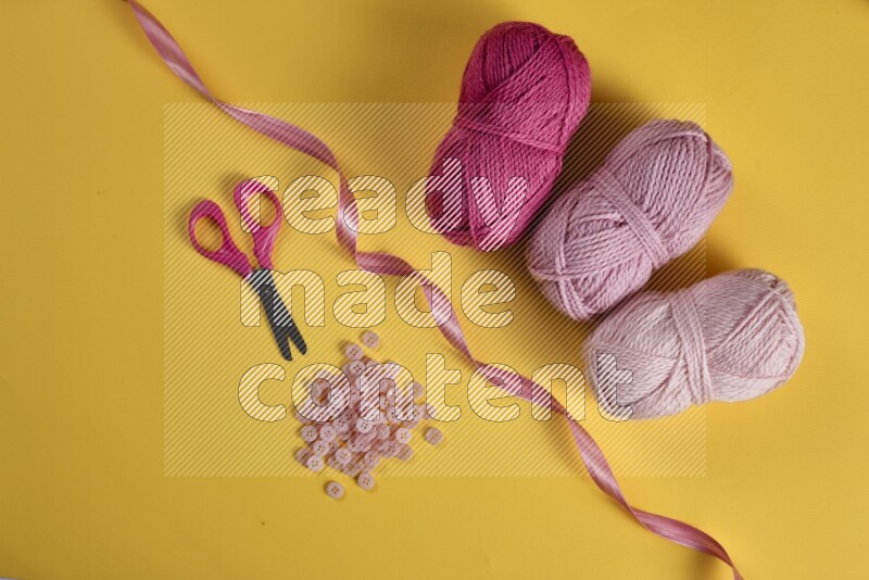 A pink collection of sewing and tailoring tools arranged on a yellow background