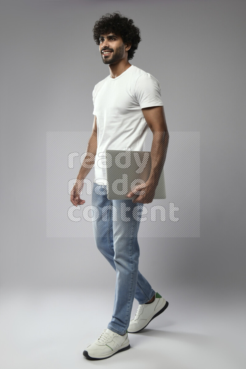 A man wearing casual standing and holding a laptop on white background