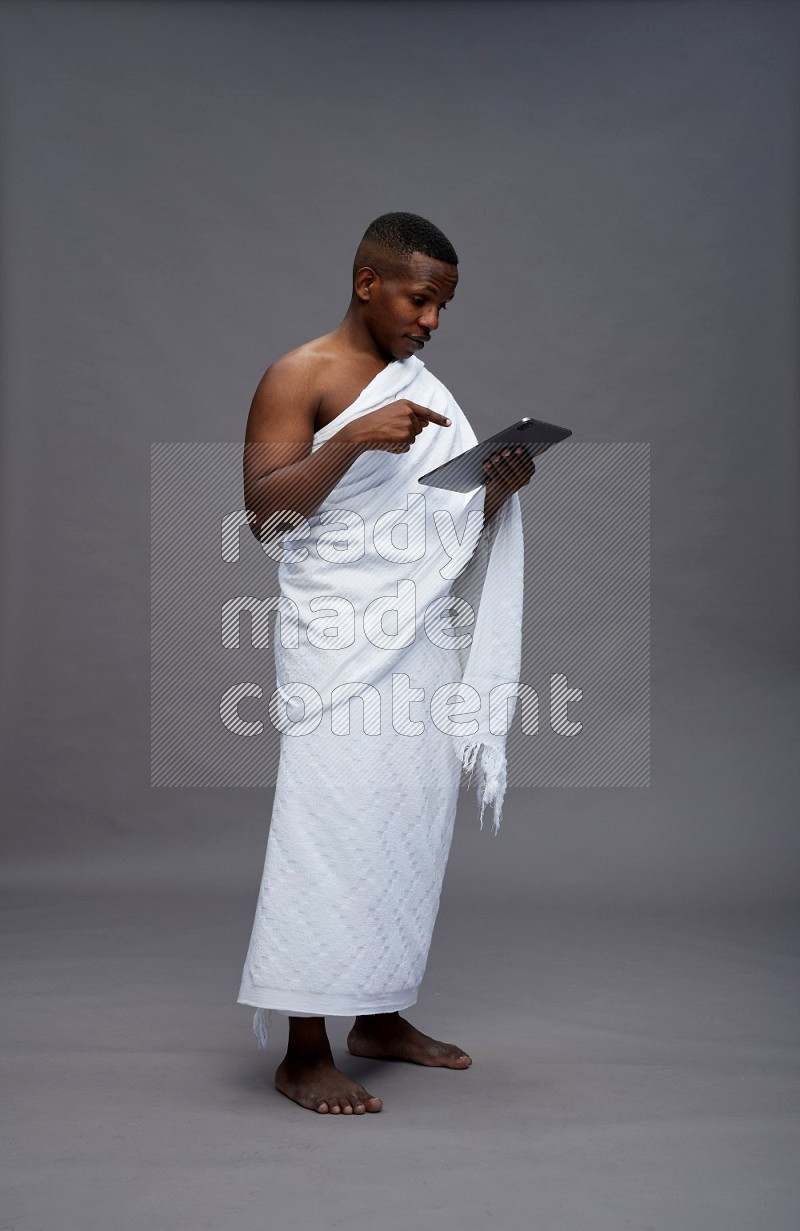 A man wearing Ehram Standing working on tablet on gray background