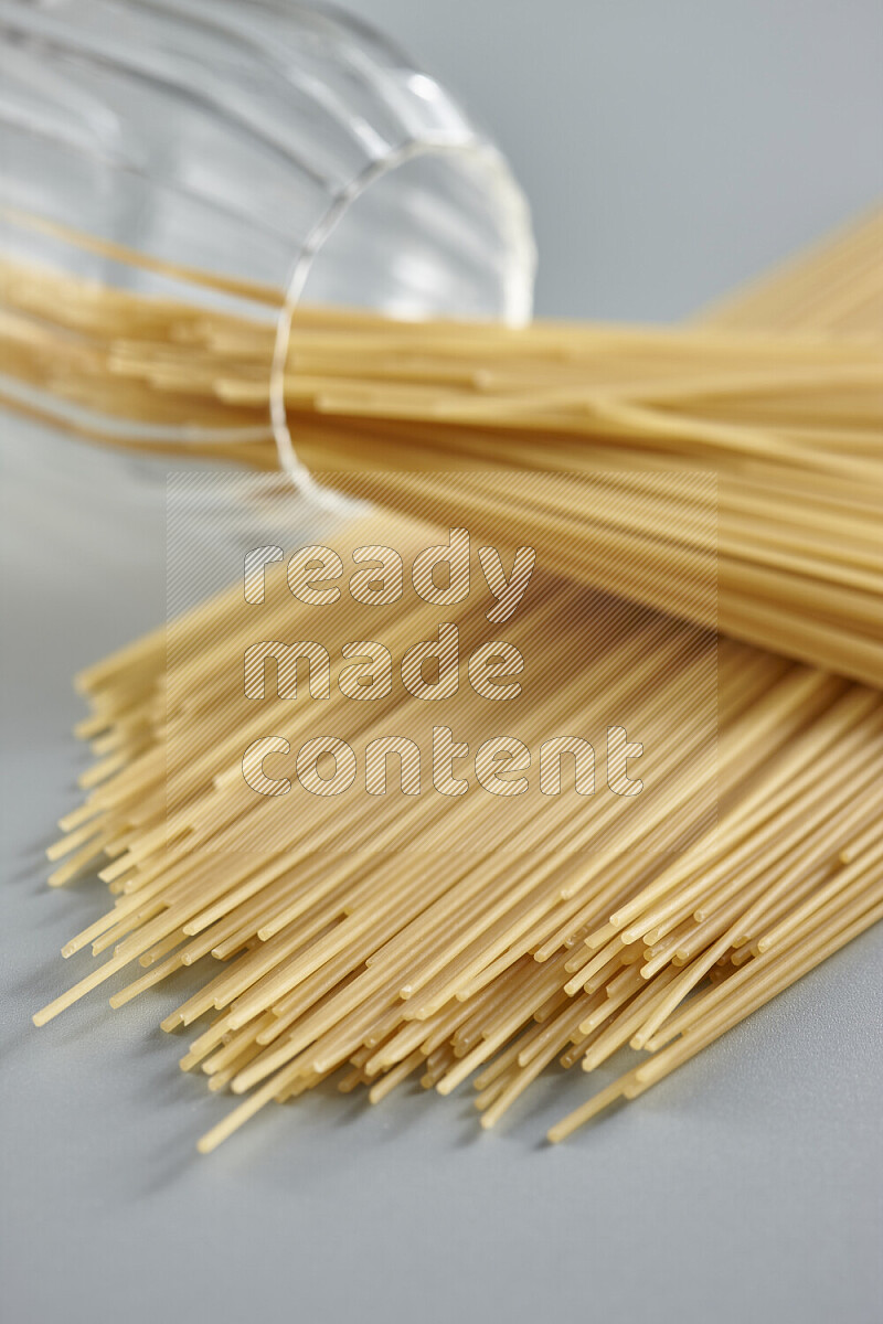 Flipped jar full of raw pasta on light blue background