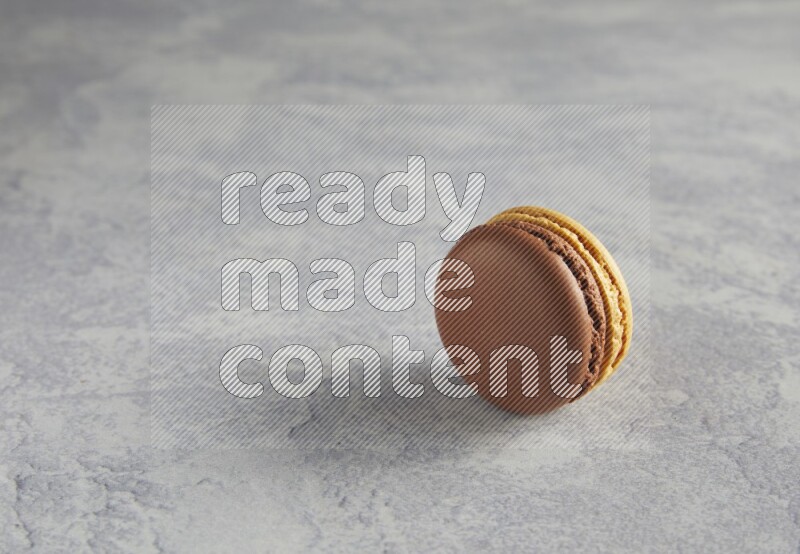 45º Shot of Yellow and Brown Chai Latte macaron on white  marble background