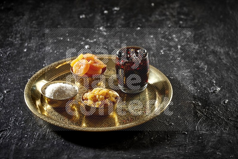 Dried fruits in metal bowls with tamarind on a tray in dark setup