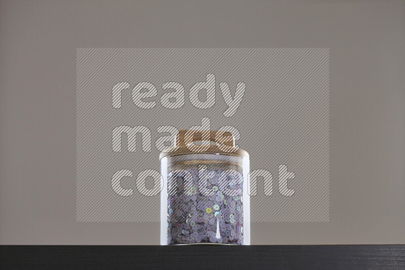 Sequins in a glass jar on black background