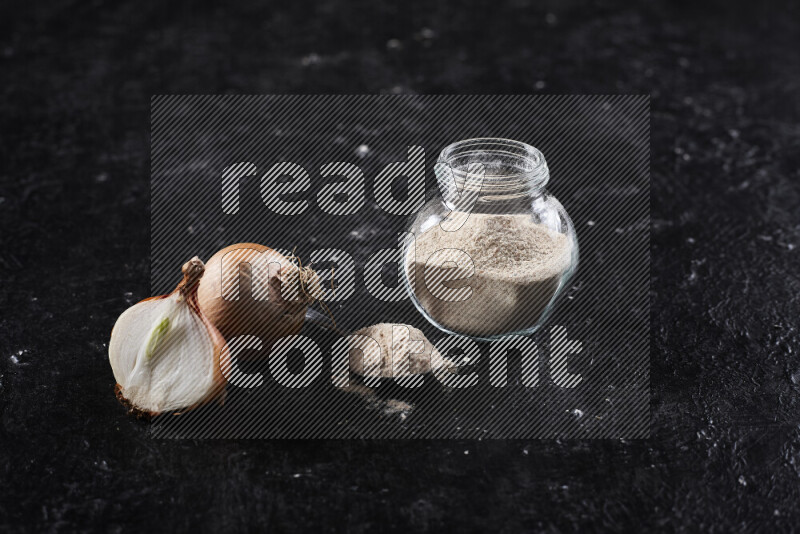 A glass jar full of onion powder on black background