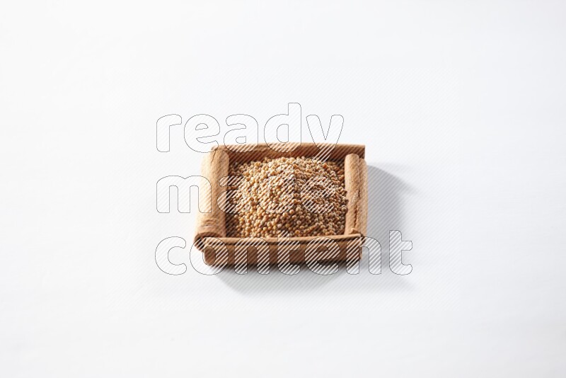 أربعة من أعواد القرفة مكونة شكل مربع بداخلها حبوب الخردل علي خلفية بيضاء