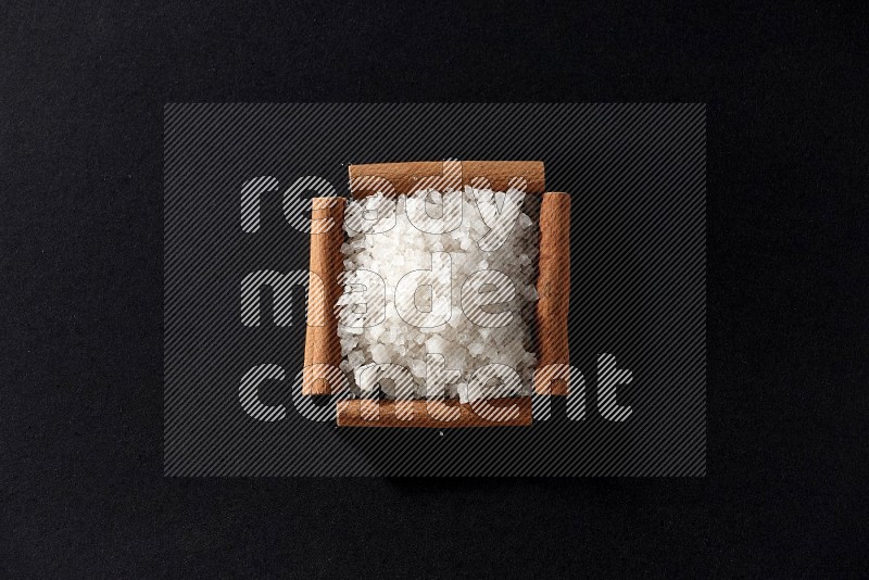 A single square of cinnamon sticks full of salt on black flooring