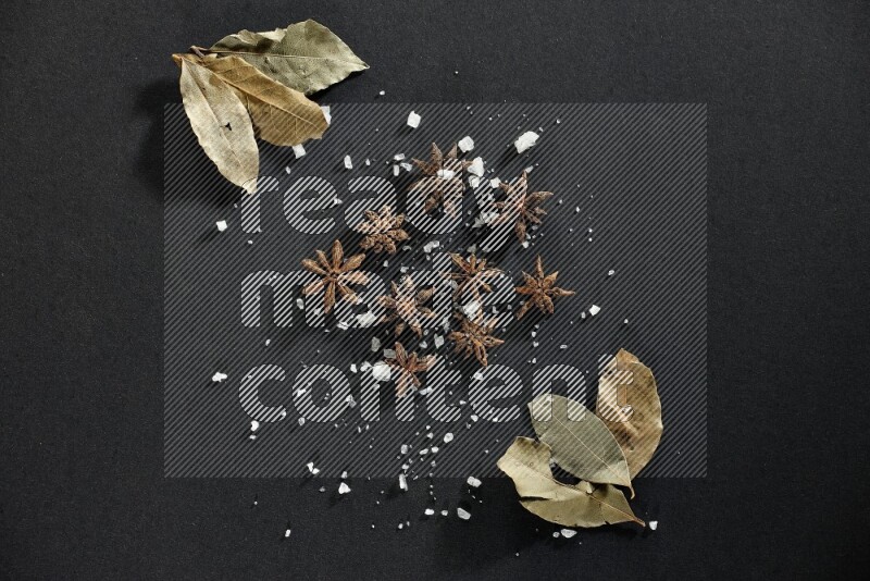 Salt, star anise and bay laurel on black flooring