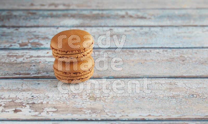 45º Shot of two Brown Maple Taffy macarons on light blue wooden background