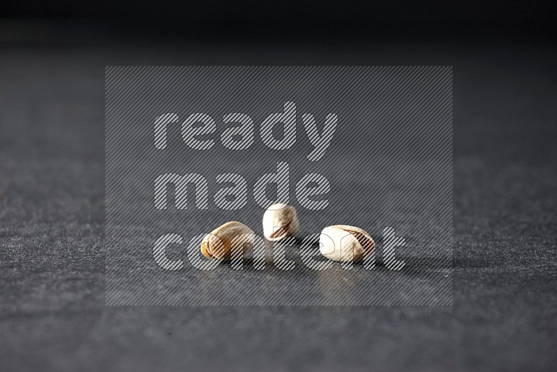3 pistachios on a black background in different angles