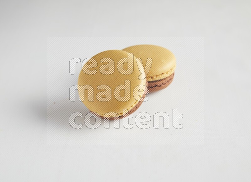 45º Shot of two Yellow and Brown Chai Latte macarons on white background