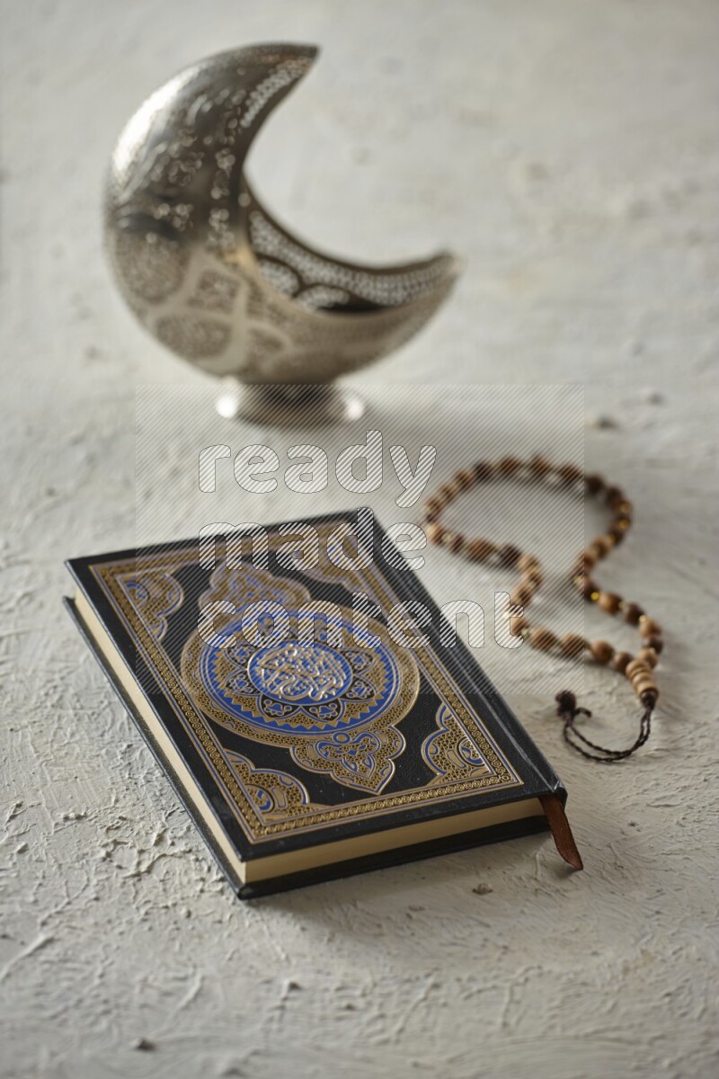 A silver lantern with different drinks, dates, nuts, prayer beads and quran on textured white background