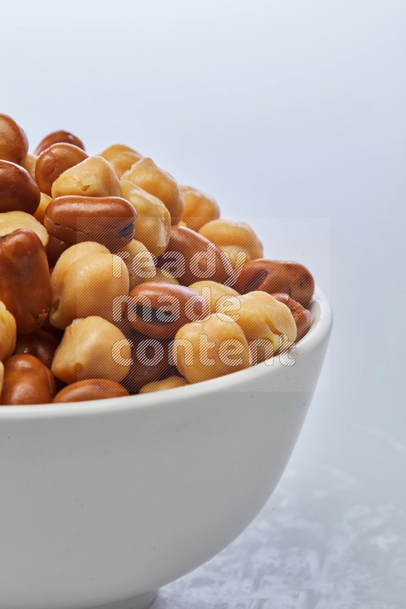 Close up shot of cooked fava beans (foul) & chickpeas on white background