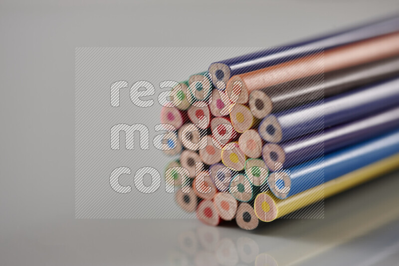 An array of colored pencils on grey background