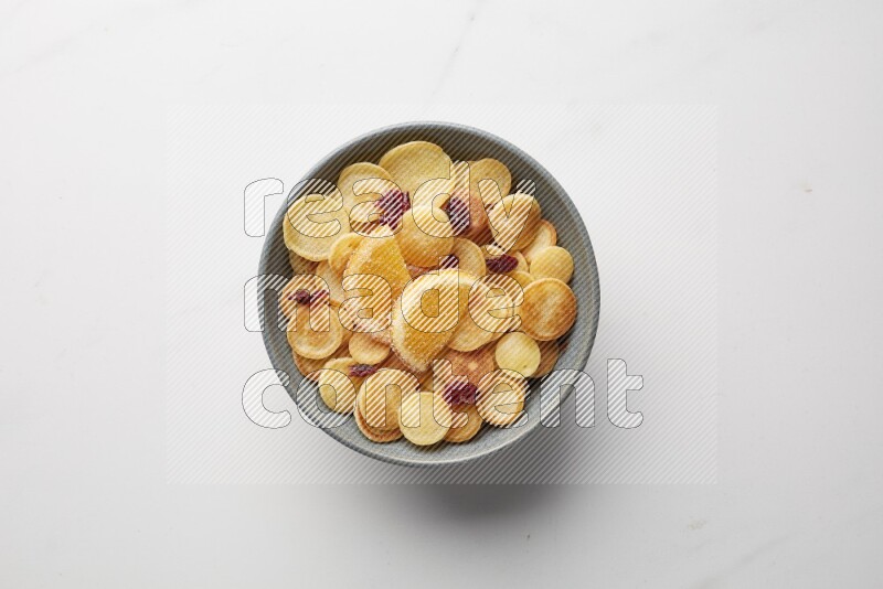 Top-view shot of orange candy cereal pancakes in a round bowl on white background