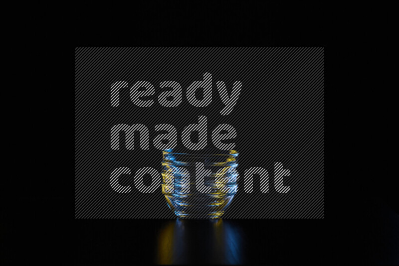 Glassware with rim light in blue and yellow against black background