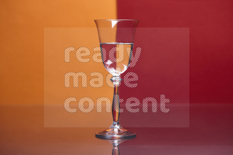 تظهر الصورة أواني زجاجية ممتلئة بالماء موضوعة على خلفية من اللونين البرتقالي والأحمر