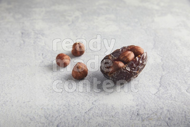 hazelnuts stuffed madjoul date on a light grey background