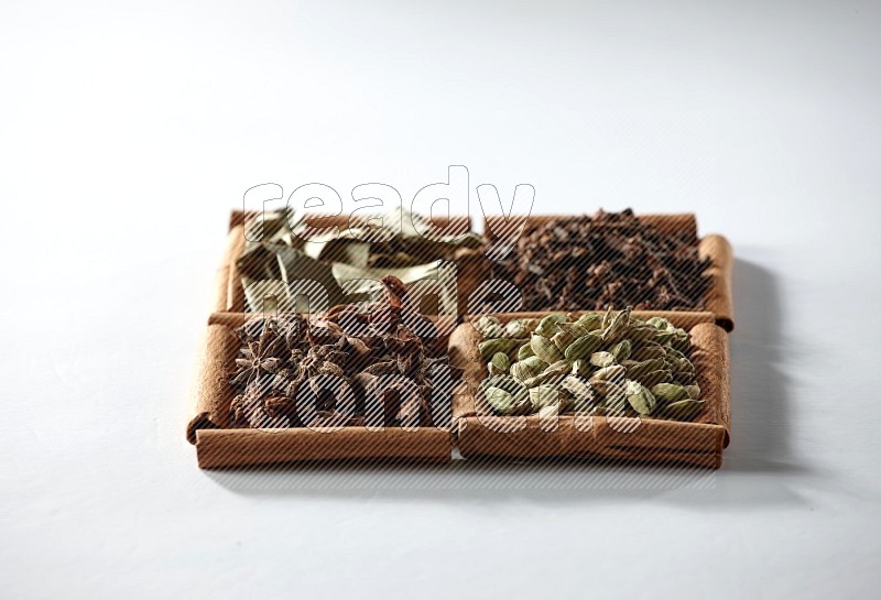 4 squares of cinnamon sticks full of cardamom, star anise, cloves and bay laurel leaves on white flooring