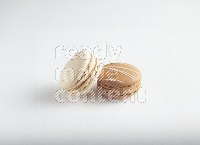 45º Shot of of two assorted Brown Irish Cream, and White Caramel fleur de sel macarons on white background