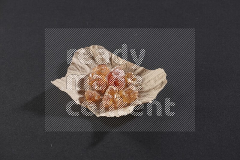 A crumpled piece of paper full of gum arabic on black flooring