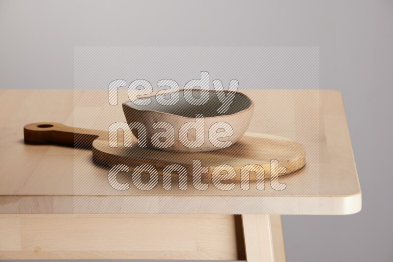 multi colored bowl placed on a  wooden oval cutting board on the edge of wooden table