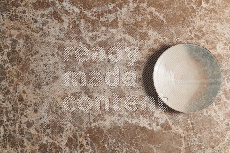 A multicolored pottery plate on beige marble background