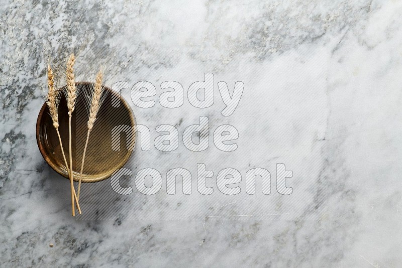 Wheat stalks on Multicolored Pottery Oven Plate on grey marble flooring, Top view
