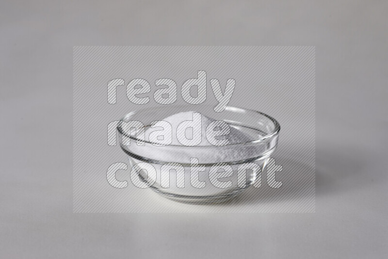 A glass bowl full of fine table salt on white background