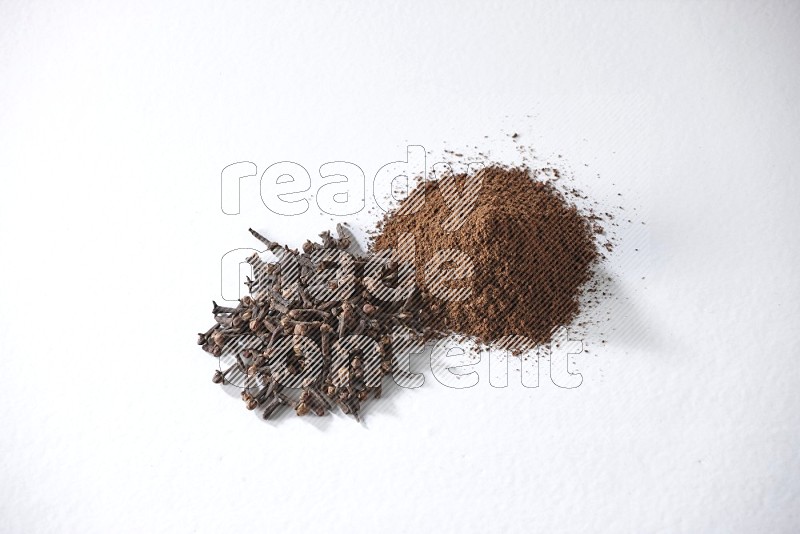 2 piles of cloves grains and cloves powder on a white flooring