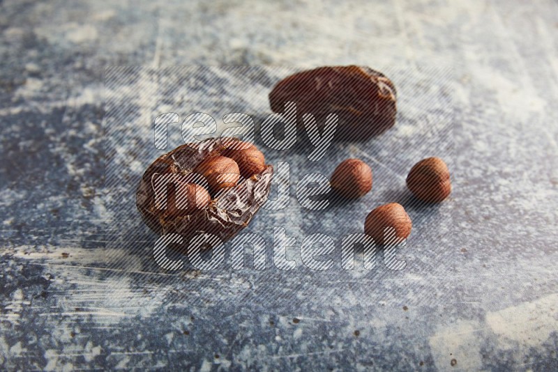 two hazelnuts stuffed madjoul dates on a rustic blue background