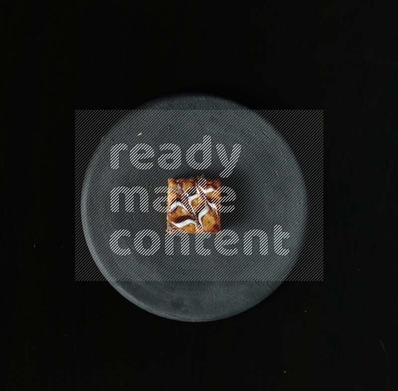 Assorted desserts in a black pottery plate on black background