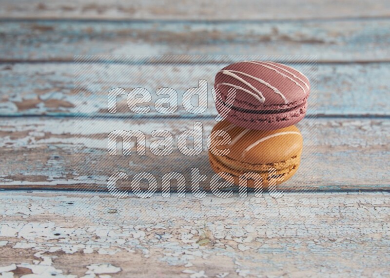 45º Shot of of two assorted Brown Irish Cream, and Red Poppy Flower macarons  on light blue background