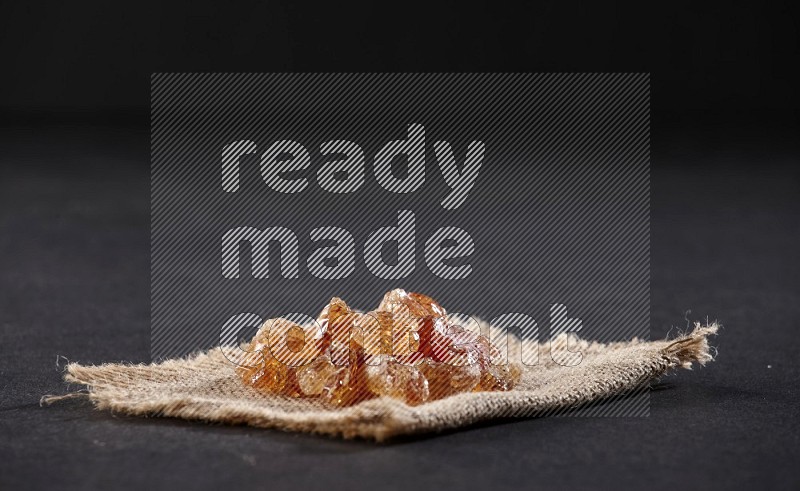 Gum arabic on a burlap piece on black flooring in different angles