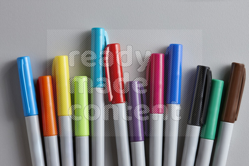 An arrangement of coloring pens in different colors on grey background