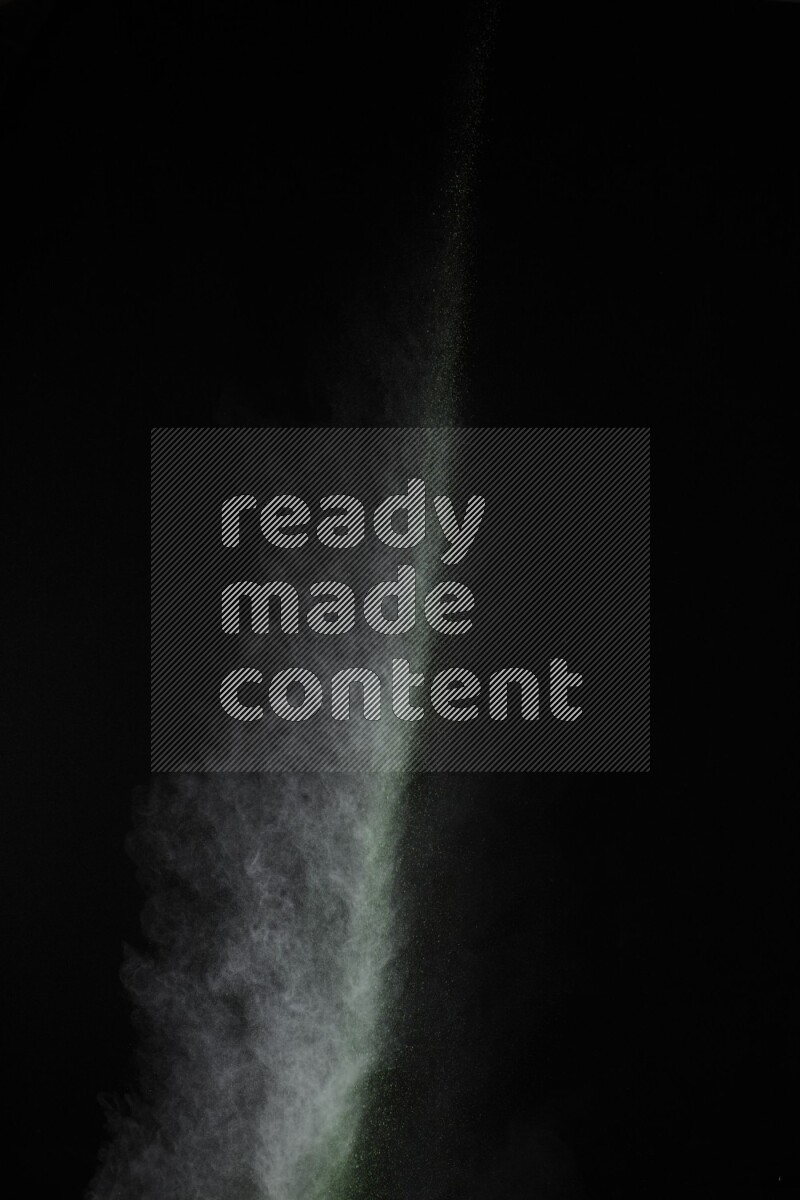 A side view of green powder explosion on black background