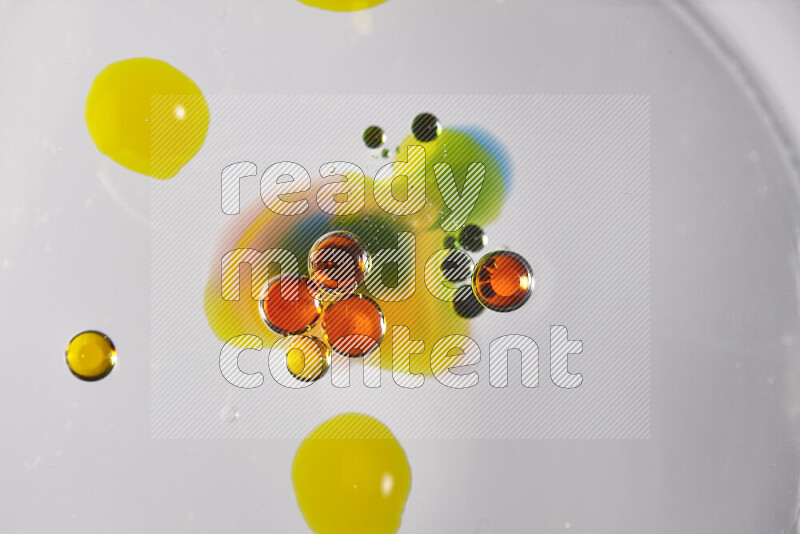 Close-ups of abstract red, blue, yellow and green watercolor drops on oil Surface on white background