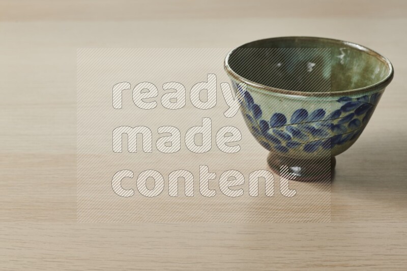A decorative pottery bowl on light wooden background