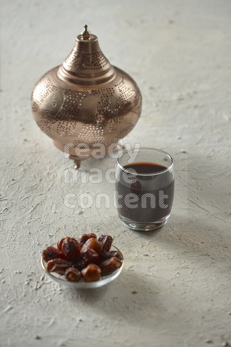 A golden lantern with different drinks, dates, nuts, prayer beads and quran on textured white background