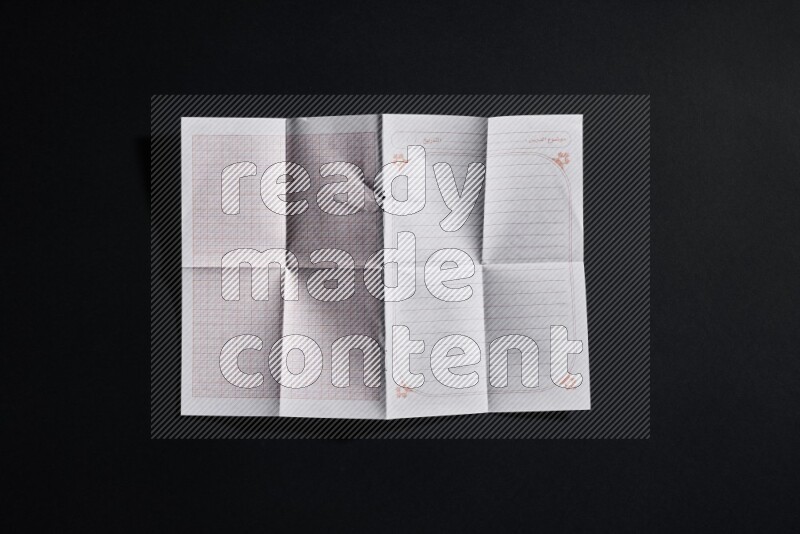 Folded notebook sheet on black background