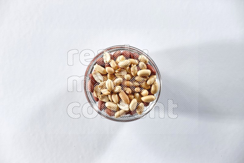 A glass bowl full of peeled peanuts on a white background in different angles