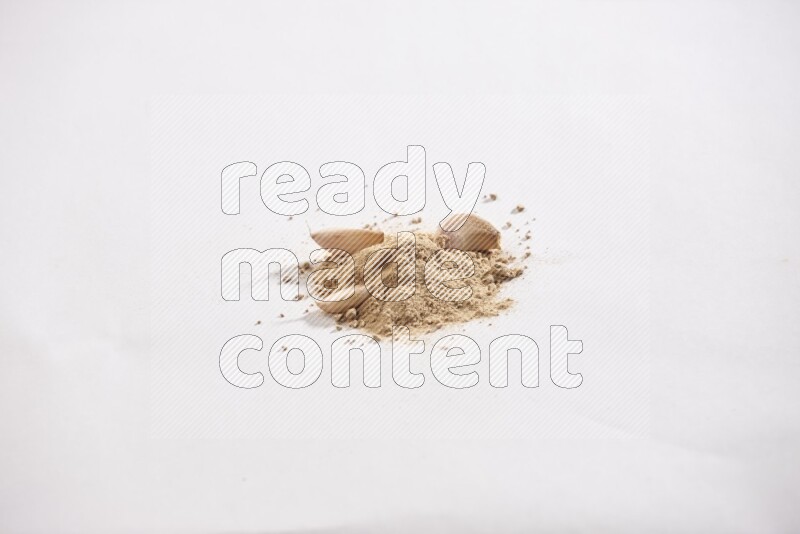 كومة صغيرة من بودرة الثوم مع بعض فصوص الثوم ورأس ثوم كاملة على خلفية بيضاء