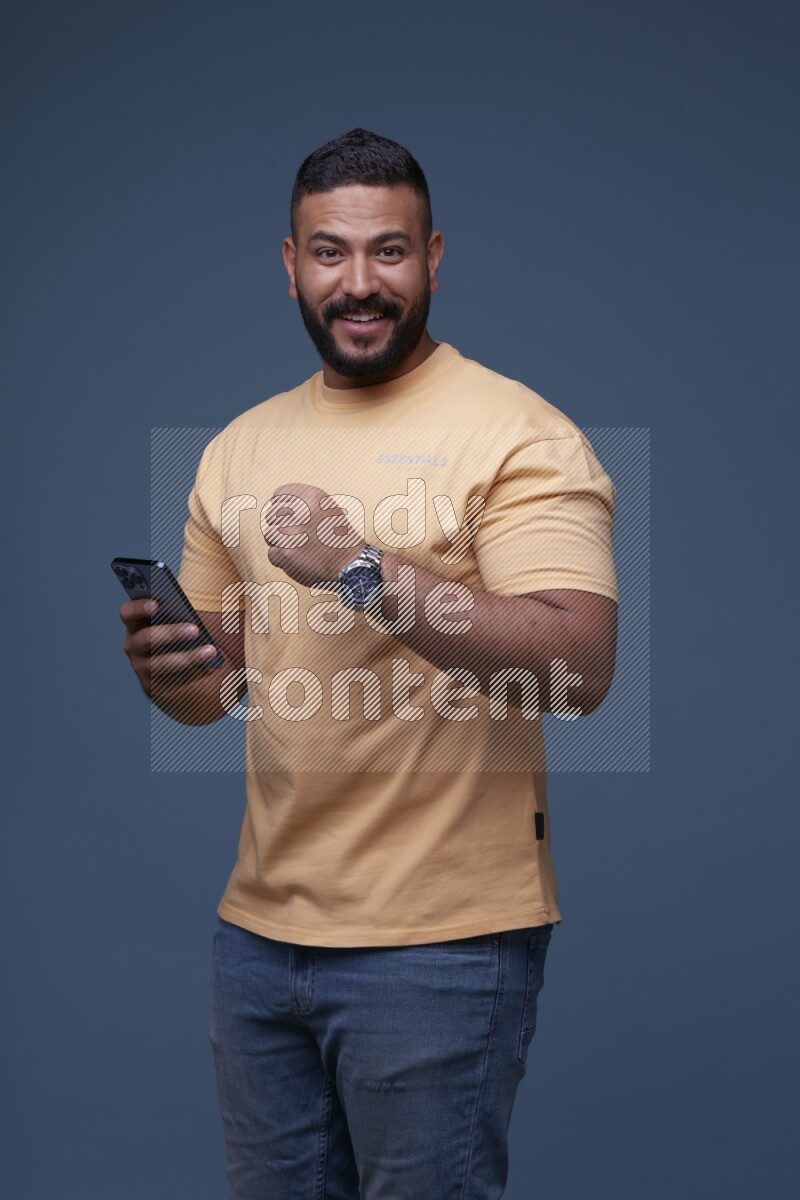 A man Texting on his phone in Blue Background wearing Orange T-shirt