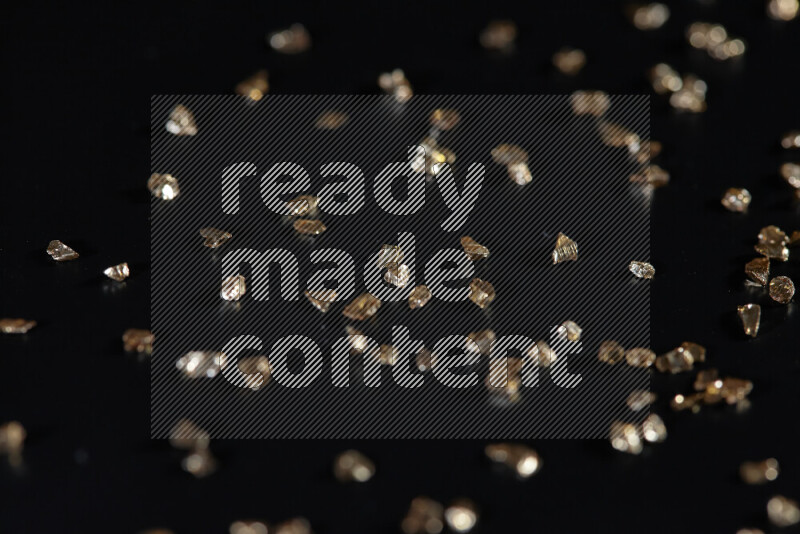 Gold shimmering fragments of glass scattered on a black background