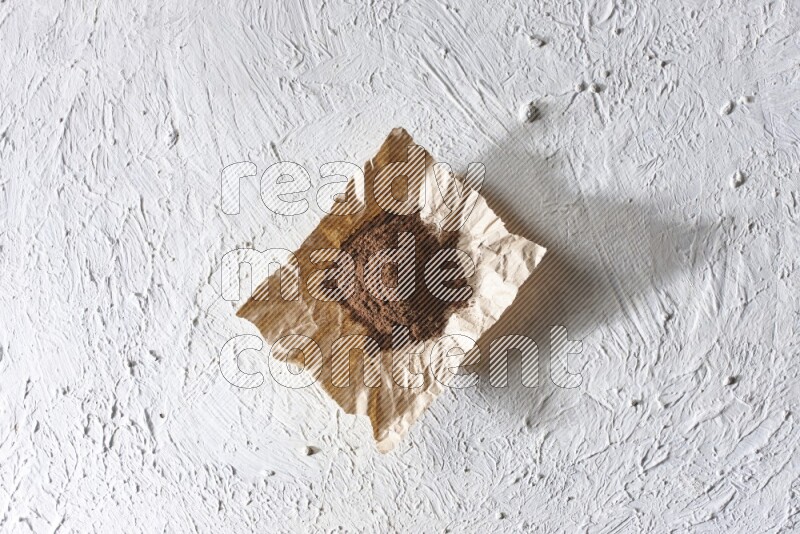 Cloves powder on crumpled piece of paper on a textured white flooring